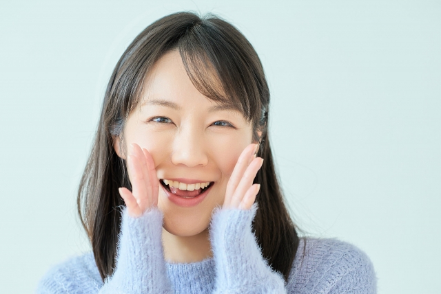 両手を口元にあてて笑顔で応援する表情の女性