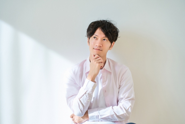 あごに手を当てて何かを考えている表情の男性