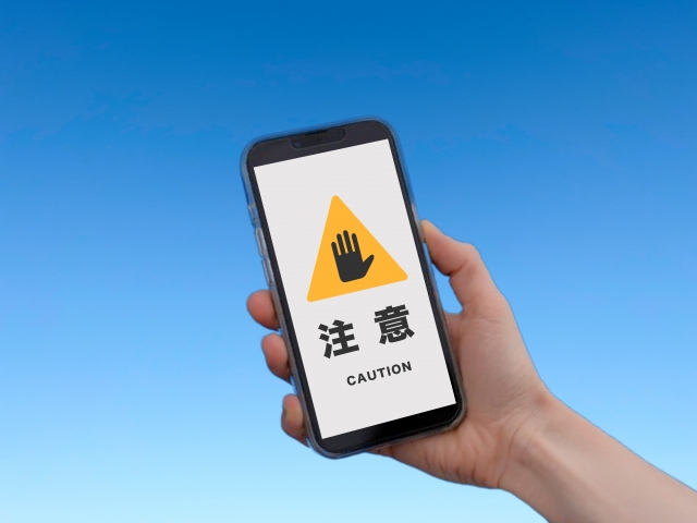 注意の文字が画面に映し出されているスマホ