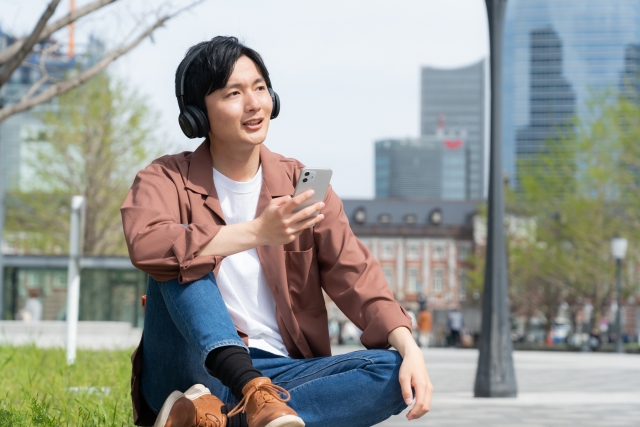 スマホを片手にヘッドフォンで音楽を聴く男性
