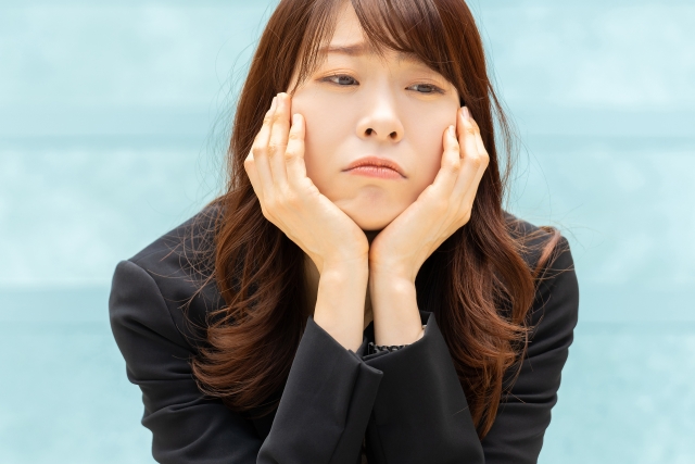 両手をあごに当てて悩んだ表情の女性
