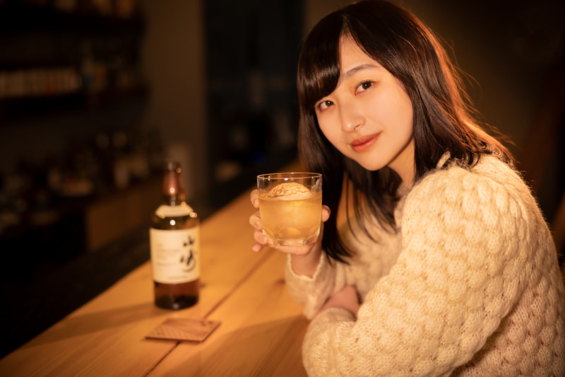 ウイスキーを手に持ちカメラ目線で見つめる女性