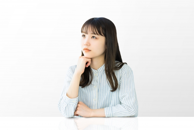 斜め上に目線をやり、何かを考えている表情の女性
