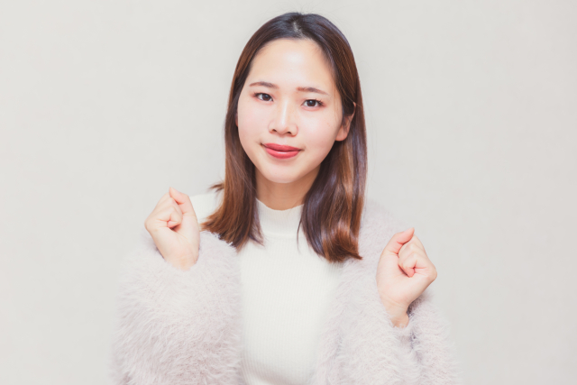 両手を挙げて喜ぶ仕草をしている女性の画像