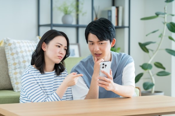 携帯を見ながら話し合っている男女の画像