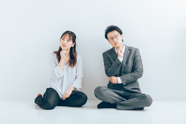 悩んだ表情で座っている男女の画像