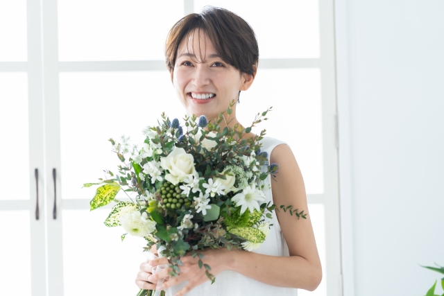 ブーケを手に持ってうれしそうな表情の女性の画像