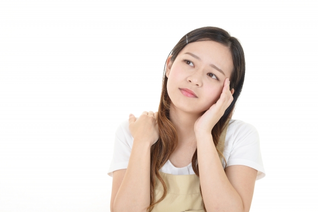 頬杖をついて悩んでいる表情の女性の画像