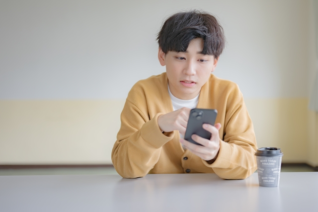 スマホを操作する男性の画像