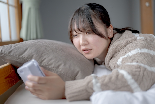 寝起きに目覚まし時計を見ている女性の画像
