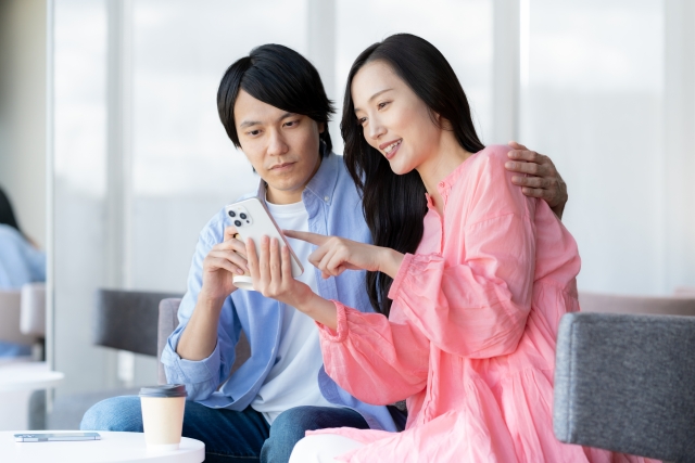 スマホを一緒に見ているカップルの画像