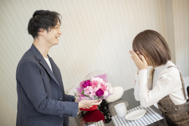男性に花束を渡され喜ぶ女性の画像