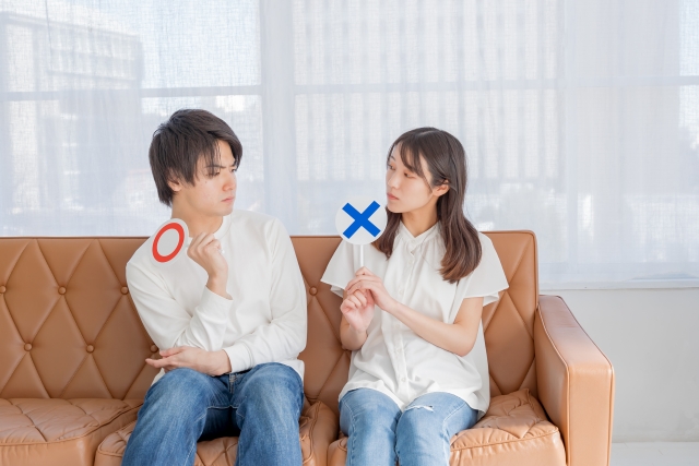 〇×の札をもって話すカップルの画像