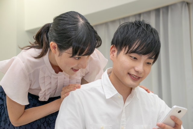 仲良くスマホを見る男女の画像
