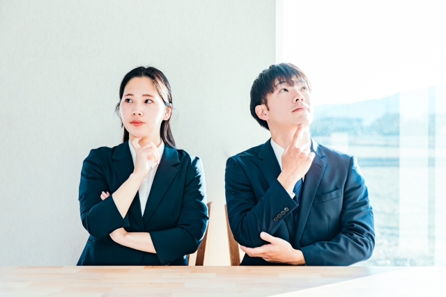 あごに手をあてて考えている表情の男女の画像