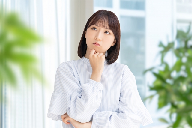 あごに手をあてて考えている表情の女性の画像