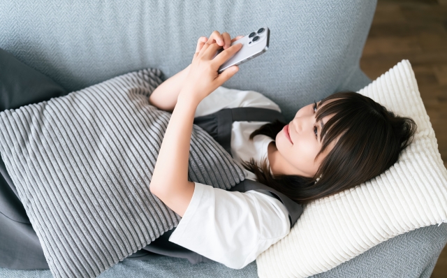 スマホを笑顔で操作する女性の画像