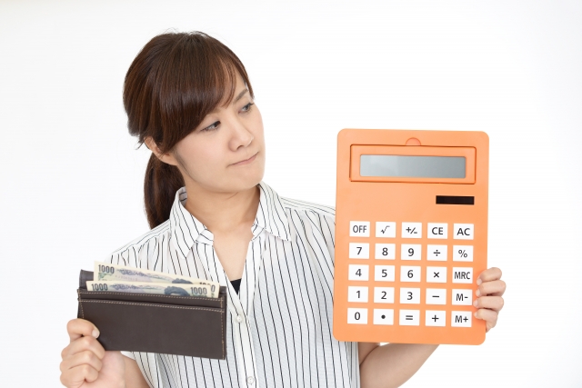 電卓と財布を手に持つ女性