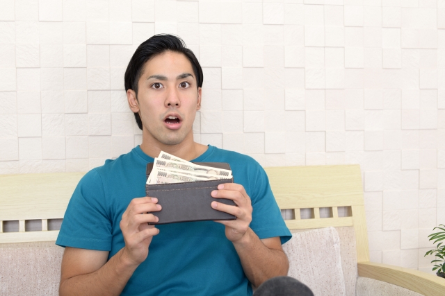 ソファに座って財布を手に持つ男性