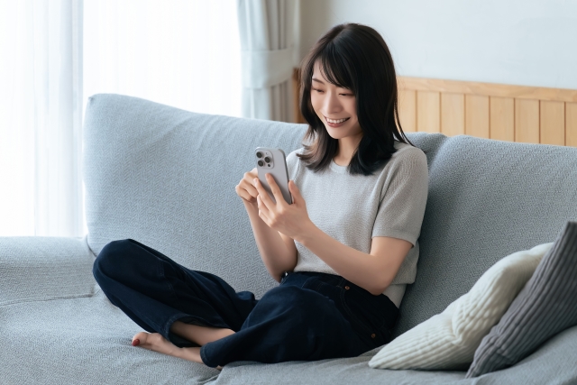 ソファに座ってスマホを操作する女性