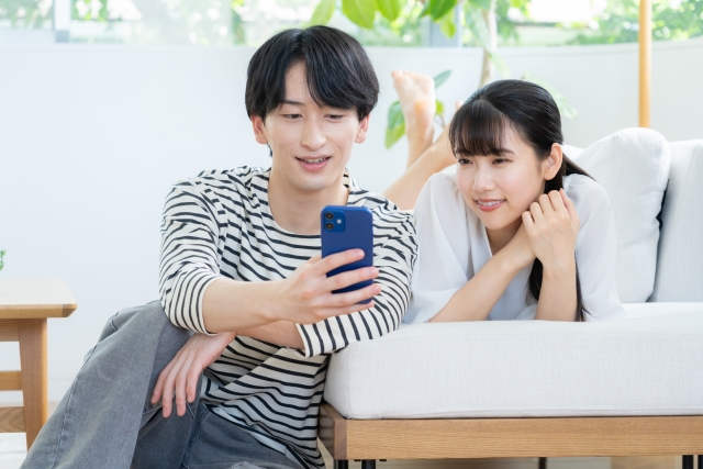 スマホを一緒に見ながら楽しそうに会話をするカップル