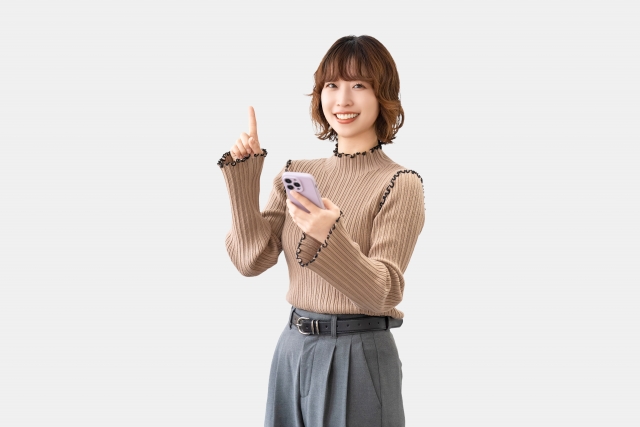 スマホを手に持ち笑顔の女性