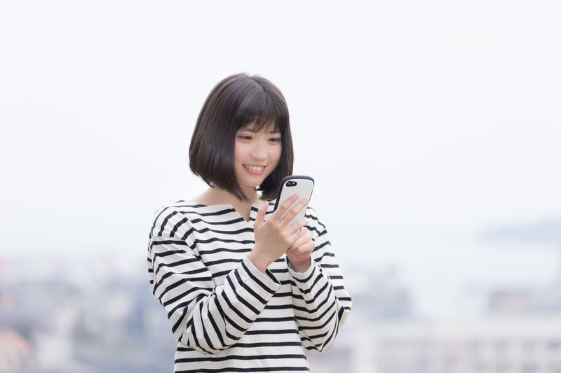 スマホを笑顔で操作する女性