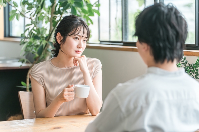 カフェで向かいに座る彼氏をにらんでいる女性