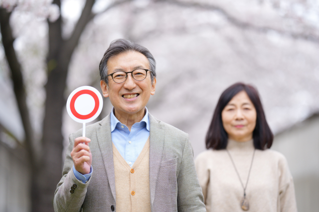 丸マークを手に持つ中高年男性と妻