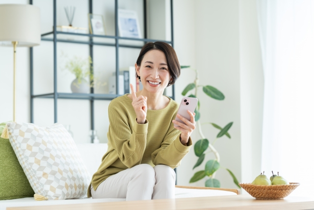 ソファに座ってスマホを手に持つ女性