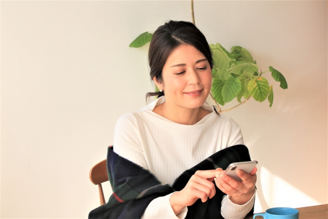自宅でスマホを操作する女性