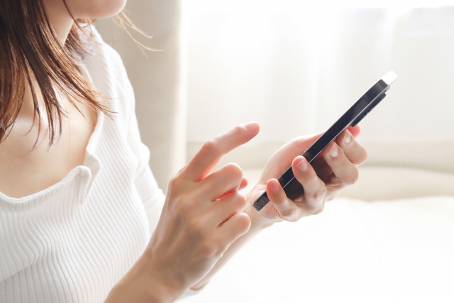 スマホを操作している女性の手元