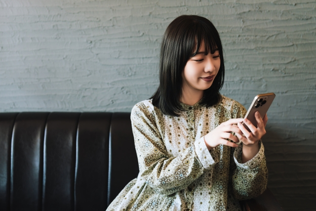 ソファに座ってスマホを操作している女性