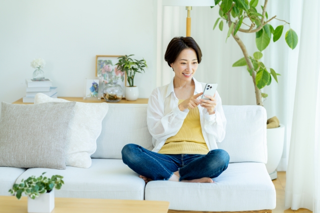 ソファに座ってスマホを操作する女性