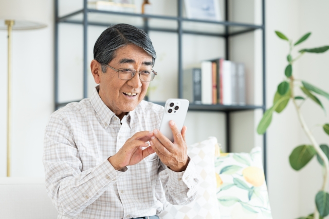 自宅でスマホを操作している中高年世代の男性