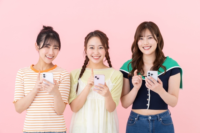スマホを手に持ち笑顔の3人の女性の画像